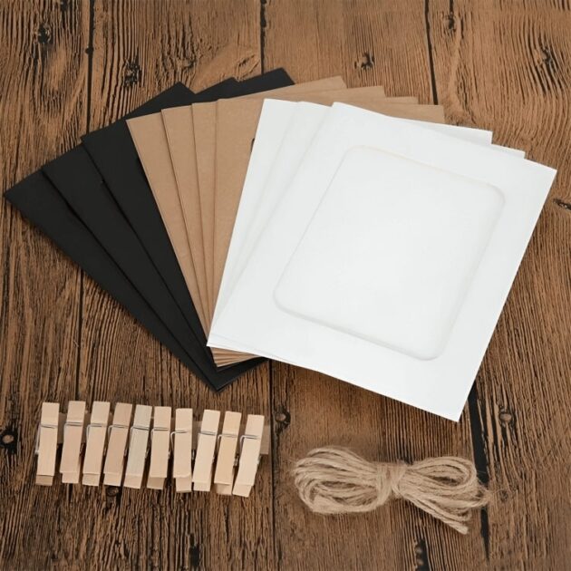 Paper photo frames in black, brown, and white placed on a wooden floor with clips and string for wall hanging.