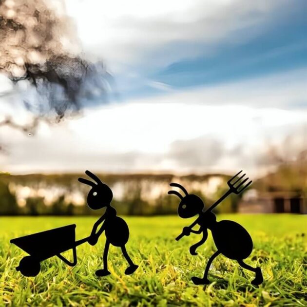 Two metal ant figurines walking across a green meadow with a scenic background and blue sky.