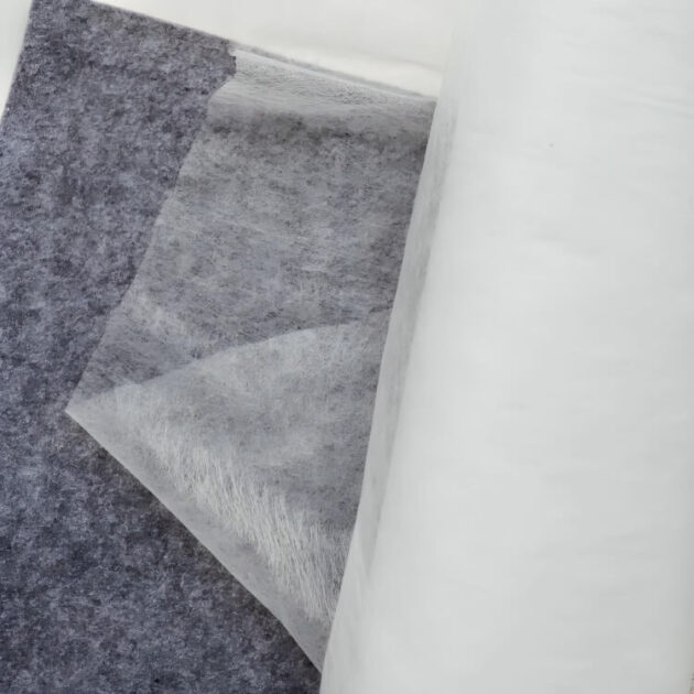 A strip of iron-on hem tape is placed on gray fabric, ideal for seamless no sew pant hemming.