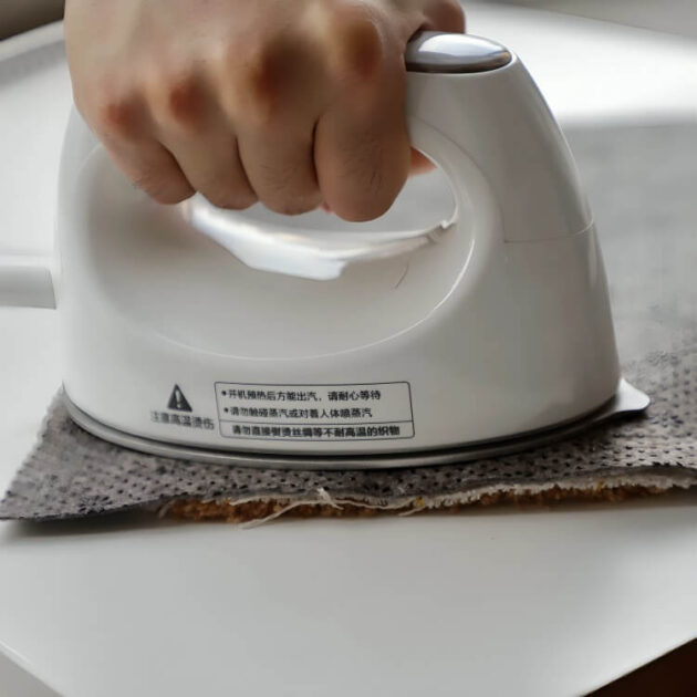 A person’s hand uses an iron to apply iron-on pants hem tape for quick and clean no sew hemming.