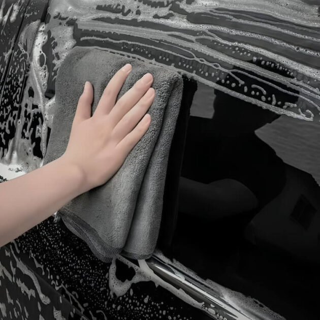 A hand is washing a car exterior using our ultra-absorbent microfiber cleaning towel.