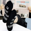 Man reading newspaper wearing mens comedy socks with I am not sleeping message.