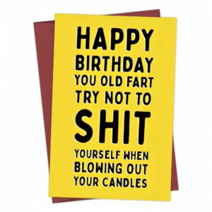 Close-up of a rude birthday card for him placed on top of a matching envelope, showing the bold message.